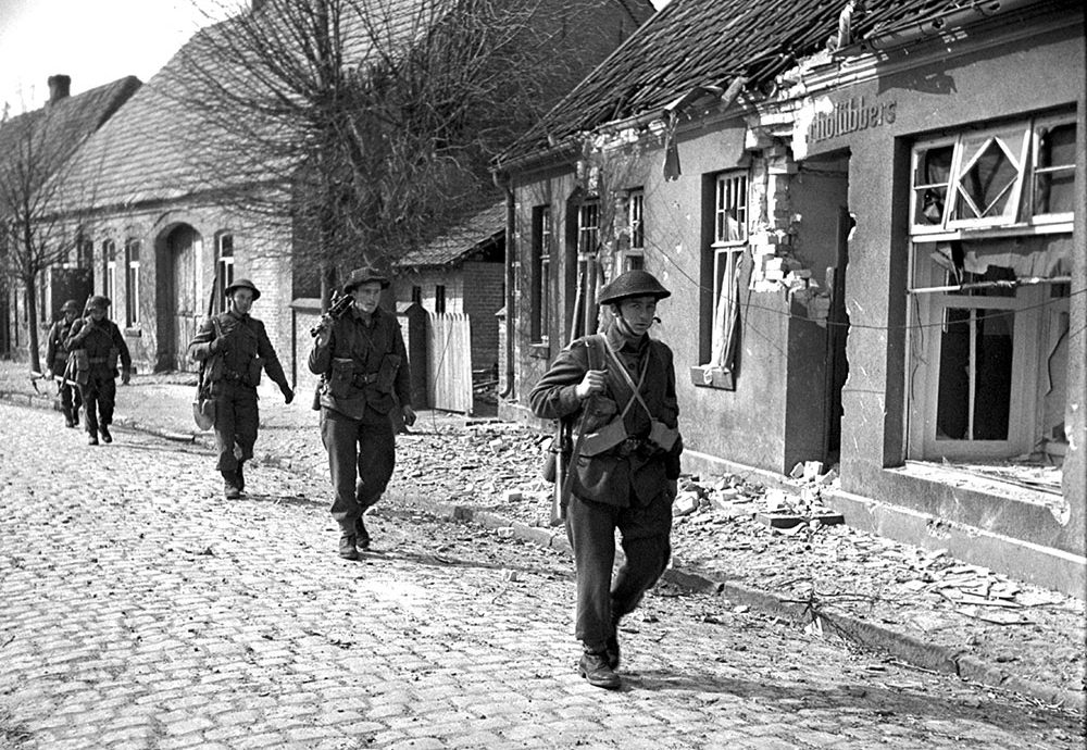 Soldiers of the Lincoln and Welland Regiment walking through the streets of Werlte looking for German paratroopers.
